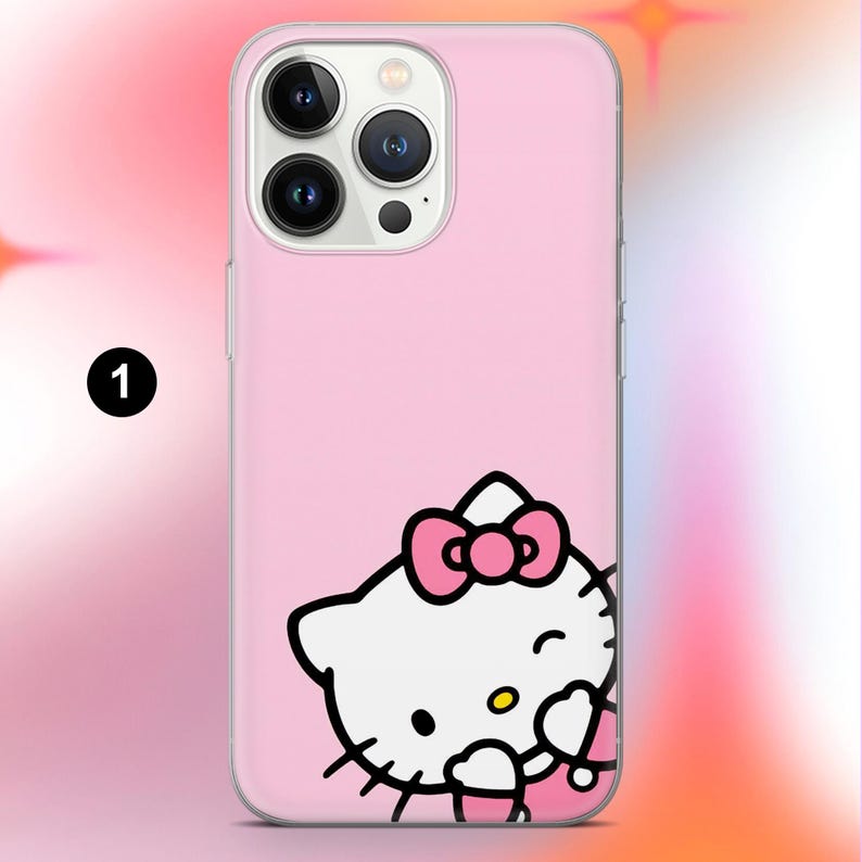 May include: Pink phone case featuring a Hello Kitty design. The case has a clear border and a smooth surface. The Hello Kitty graphic is white with a pink bow and is winking.