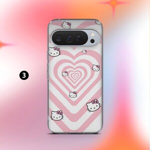May include: A clear phone case featuring a pink and white heart pattern with multiple Hello Kitty character illustrations. The case has a camera cutout and a number 3 in a black circle.
