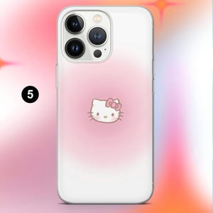 May include: Clear phone case with a pink gradient background and a Hello Kitty graphic. The case has a white border and a camera cutout. The Hello Kitty graphic is centered and features a pink bow.