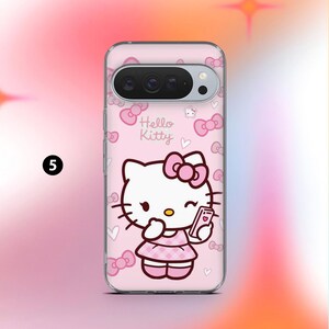 May include: A clear phone case with a pink background featuring a Hello Kitty design. The design includes the Hello Kitty character holding a phone, bows, and the words "Hello Kitty". The case is designed to fit a phone with a camera bar.