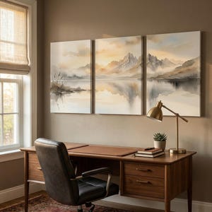 May include: A triptych wall art set featuring a watercolor-style landscape of mountains, a calm lake, and reeds in soft shades of beige, gray, and white. The three rectangular canvases are hung side-by-side, depicting a serene, misty mountain scene.