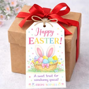 May include: A brown gift box tied with a red ribbon and a decorative tag. The tag reads "Happy EASTER!" with a basket of Easter eggs and bunny ears. The tag also says "A sweet treat for somebunny special!" and "FROM: SOPHIA".