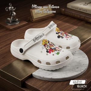 Op de afbeelding: Witte Mickey and Friends kinderslippers. De slippers hebben een kleurrijke afbeelding van Mickey Mouse en vrienden. Op de band staat "FRIENDS". De slippers staan op een marmeren en houten ondergrond.