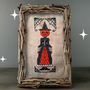 A creepy, primitive-style Halloween cross-stitch pattern featuring a pumpkin-headed witch in a Victorian dress