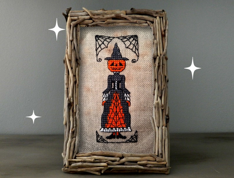 A creepy, primitive-style Halloween cross-stitch pattern featuring a pumpkin-headed witch in a Victorian dress