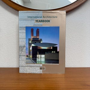 May include: A hardcover book titled "International Architecture YEARBOOK" with a photograph of a modern building on the cover. The book has a silver and tan color scheme with the number "No. 2" at the bottom.