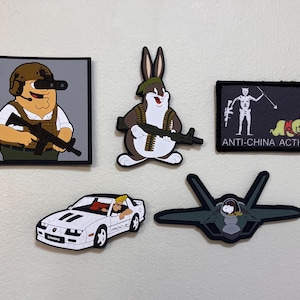 May include: Collection of patches featuring cartoon characters and vehicles. Includes a Peter Griffin-like character in military gear, Bugs Bunny with a machine gun, a black patch with the text "ANTI-CHINA ACTION", a white sports car, and a fighter jet.