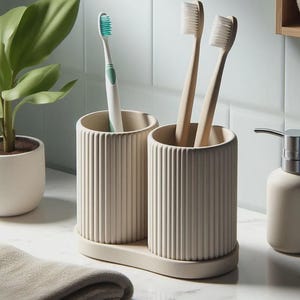 May include: A beige toothbrush holder with two compartments, each holding toothbrushes. One compartment has a green and white toothbrush, the other has two wooden toothbrushes. A matching soap dispenser is to the right.