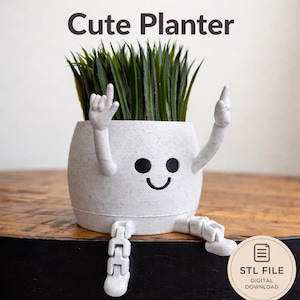 May include: A whimsical, light gray planter with a smiling face, arms raised, and legs dangling. The planter holds faux green grass and features the text "Cute Planter". A digital download STL file is also available.