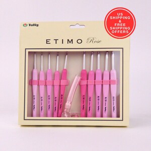 May include: A set of pink crochet hooks in a beige box. The hooks are various shades of pink with silver metal tips. The box has the text "ETIMO Rose" and "Tulip". The hooks are held in place with pink rubber bands.