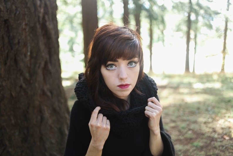 Taking off the hood of a hooded cowl in black