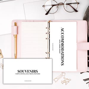 Peut inclure: Une composition à plat avec un agenda rose, un stylo doré et des lunettes rondes sur un ordinateur portable. Une tasse de café blanche repose sur une écharpe grise, et un petit bol de trombones est à proximité. Une carte indique "ACCOMMODATIONS".