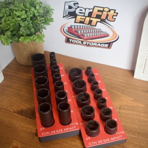 Könnte beinhalten: Zwei rote Steckschlüsselsortierer mit schwarzen Steckschlüsseln unterschiedlicher Größen. Die Sortierer sind mit "ICON 3/8 SAE IMPACT" beschriftet und enthalten die Größen 3/4 und 11/16. Der Hintergrund zeigt ein Schild mit "PerFit FIT TOOL STORAGE".