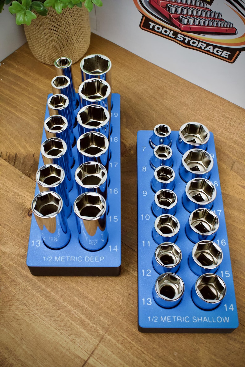 May include: Two blue socket organizers with chrome sockets. The left organizer is labeled "1/2 METRIC DEEP" and the right is labeled "1/2 METRIC SHALLOW". The sockets are numbered from 7 to 19. The image also shows a "TOOL STORAGE" sign.