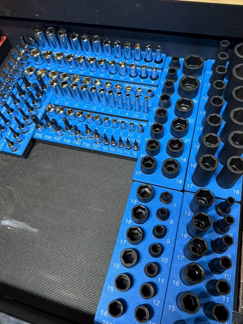 May include: Organized set of sockets and bits in a blue tool organizer. The sockets are various sizes and shapes, including hex and star patterns. The tools are arranged neatly, ready for use in a workshop or garage.