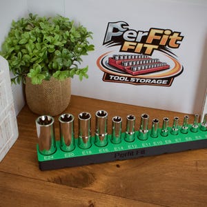 Könnte beinhalten: Ein Satz verchromter Steckschlüssel in einem grünen Halter, mit Größen von E4 bis E24. Der Halter steht auf einer Holzoberfläche, mit einer Pflanze in einem Jutesack und einem dekorativen weißen Holzelement im Hintergrund. Das Logo "PerFit" ist sichtbar.