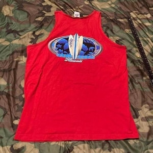 May include: Red tank top with a graphic featuring two surfboards and the words "North Shore Hawaii". The graphic is in an oval shape with blue and white accents. The tank top is sleeveless.
