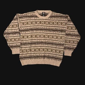 May include: A long-sleeve crew neck sweater featuring a repeating horizontal pattern of dark brown and tan geometric shapes. The knit garment has a ribbed collar, cuffs, and hem, with a consistent textured weave throughout the entire piece.