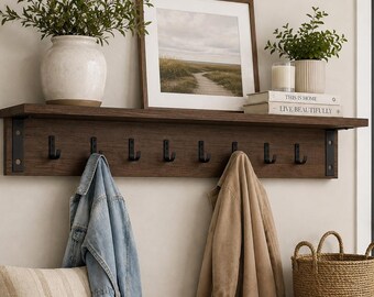 May include: A dark wood wall-mounted shelf featuring eight black metal hooks. The text reads TRENDY SHELF WITH HOOKS PDF PLAN BEGINNER FRIENDLY. The shelf holds a white vase with greenery, a framed landscape print, and a stack of books.