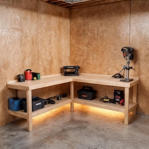 May include: A light-colored wooden workbench with an L-shape design. The workbench has a lower shelf and is illuminated with warm lighting. Various tools, including a drill press, are placed on the workbench. There are also toolboxes and other equipment.
