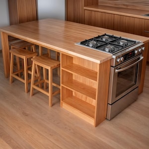 Op de afbeelding: Een houten keukeneiland met een ingebouwde gaskookplaat en oven. Het eiland heeft een lichtbruine afwerking, met drie houten krukken eronder. Het eiland heeft ook open schappen voor opslag.