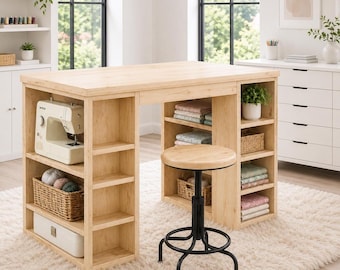 May include: A light wood craft table with integrated shelving units on both sides, featuring a sewing machine, woven baskets, and folded fabric. A round wooden stool with a black metal base and footrest is positioned in front of the table.