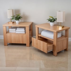 Könnte beinhalten: Zwei Nachttische aus Holz mit natürlicher Oberfläche. Jeder Nachttisch hat eine Schublade, ein Regal und eine quadratische Lampe mit beigem Schirm. Kleine Topfpflanzen stehen oben. Eine Schublade ist geöffnet.