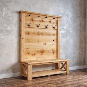 May include: A wooden entryway bench with a back panel featuring multiple black hooks for hanging items. The bench is made of light-colored wood and has a lower shelf and an X-shaped design on the sides.