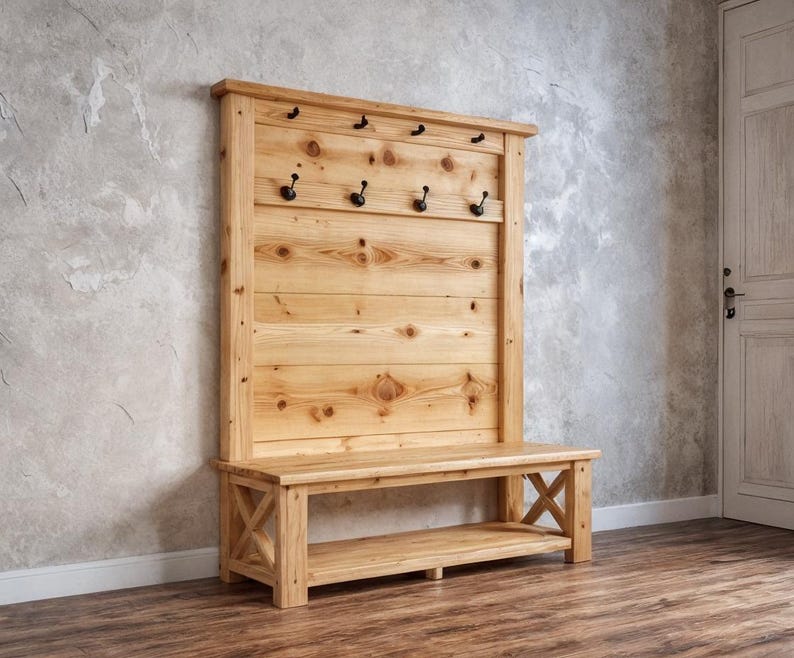 May include: A wooden hall bench with a back panel featuring several black hooks for coats and bags. The bench is constructed from light-coloured wood and includes a lower shelf and an X-shaped design on the sides.