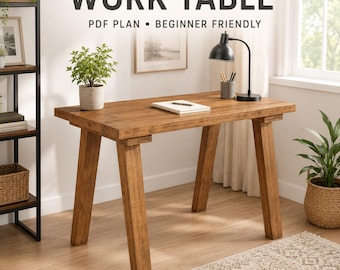 May include: A rectangular wooden work table with four angled legs and a natural brown finish. The text WORK TABLE PDF PLAN BEGINNER FRIENDLY is displayed above the table. A white notebook, a black desk lamp, and a small potted plant sit on top.