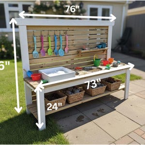 May include: A wooden outdoor play kitchen, 76 inches wide and 46 inches tall, with a white frame and natural wood accents. It features a sink, a cooking area, and hanging utensils. Includes a lower shelf with three wicker baskets, and is 24 inches deep.