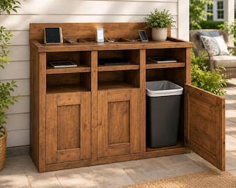 May include: A brown wooden storage cabinet with three sections, featuring open shelves for electronic devices and a lower cabinet area. One section contains a tall, rectangular black trash bin with a white liner, and the door is open.