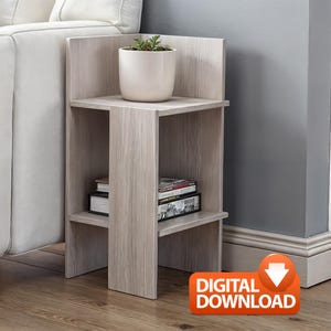 Peut inclure: Une table d'appoint en bois clair avec deux étagères. Un pot en céramique blanche avec une petite plante est posé sur l'étagère supérieure. Des livres et des magazines sont sur l'étagère inférieure. La table est à côté d'un canapé blanc.