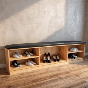 Puede incluir: Un zapatero de madera con una parte superior acolchada negra. El mueble tiene varios compartimentos llenos de varios zapatos, incluyendo zapatillas y tacones. La madera tiene un acabado claro, y el fondo es de color neutro.