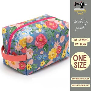 May include: A rectangular makeup pouch featuring a blue background with a colorful floral pattern of red, pink, yellow, and light blue flowers and green leaves. It has a bright pink zipper and a matching pink side handle for carrying.