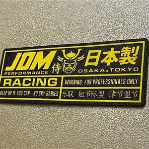 May include: Black and yellow sticker with the text "JOM PERFORMANCE RACING" and "JAPANESE" in Japanese characters. The sticker also includes the text "OSAKA.TOKYO" and "WARNING: FOR PROFESSIONALS ONLY".