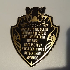 Könnte beinhalten: Ein schwarzer und goldener Schild-förmiger Aufkleber mit einer Panther-Silhouette und dem Text "BURY ME IN THE OCEAN WITH MY ANCESTORS WHO JUMPED FROM THE SHIPS, BECAUSE THEY KNEW DEATH WAS BETTER THAN BONDAGE".
