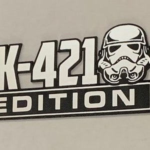 May include: Black and white graphic of a Star Wars Stormtrooper helmet with the text "TK-421 EDITION" below it.