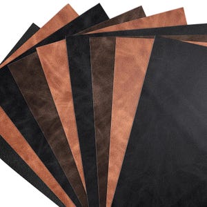 Könnte beinhalten: Fächerförmige Anordnung von Lederplatten in verschiedenen Braun- und Schwarztönen. Die Platten haben eine glatte, matte Oberfläche und sind so angeordnet, dass die verschiedenen Farben und Texturen zur Geltung kommen. Das Leder scheint von hoher Qualität zu sein, geeignet für Bastel- oder Designprojekte.