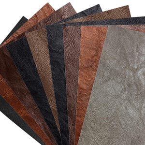 May include: A selection of textured faux leather sheets in shades of brown, black, and grey. The sheets have a wrinkled appearance, with colours ranging from dark charcoal to light taupe.