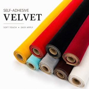 May include: Rolls of self-adhesive velvet fabric in various colors, including yellow, red, black, and burgundy. The text "SELF-ADHESIVE VELVET" is displayed, along with "SOFT TOUCH • EASY APPLY". The rolls are tightly wound and ready for use.