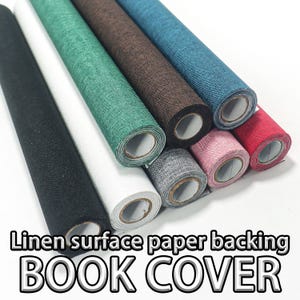 Pode incluir: Variedade de rolos de capas de livros de papel de superfície de linho em várias cores, incluindo preto, branco, verde, castanho, azul, rosa, cinza e vermelho. O texto "Linen surface paper backing BOOK COVER" está visível.