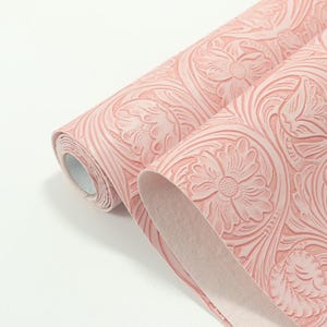 May include: Two rolls of pink wallpaper with a floral and leaf pattern. The wallpaper is embossed with a raised design, creating a textured look. The rolls are partially unrolled, revealing the pattern.