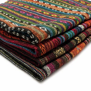 Puede incluir: Una pila de tela doblada con una textura tejida y rayas horizontales en colores vibrantes que incluyen naranja, verde, azul, rojo y negro. El tejido muestra patrones geométricos intrincados y pequeñas formas repetitivas en todo el diseño.