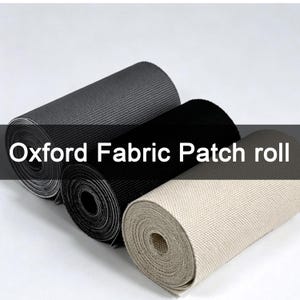 Op de afbeelding: Drie rollen Oxford-stof patchmateriaal naast elkaar geplaatst, met een geweven textuur. De rollen zijn uitgevoerd in donkergrijs, zwart en off-white. De tekst Oxford Fabric Patch roll is over het midden van de afbeelding geplaatst.