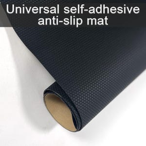 Könnte beinhalten: Gerollte, schwarze, selbstklebende Anti-Rutsch-Matte mit wabenförmiger Textur. Der Text "Universal self-adhesive anti-slip mat" ist oben zu sehen. Die Matte zeigt eine braune Rückseite.