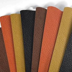 Puede incluir: Muestras de cuero en varios colores, incluyendo naranja, negro, marrón y dorado. Las muestras están dispuestas en forma de abanico, mostrando la textura y las variaciones de color del material. El cuero tiene un grano texturizado.