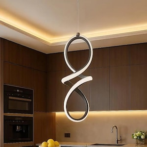 May include: Modern, abstract pendant light fixture with a black and white design, suspended from the ceiling. The light fixture is in a kitchen with dark wood cabinetry, a marble countertop, and a breakfast bar with two chairs.