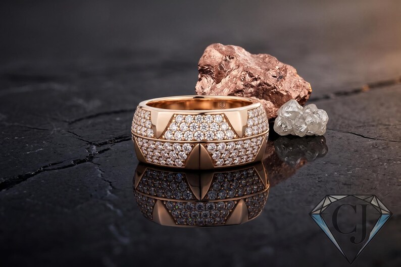 May include: A rose gold ring, heavily set with small diamonds, reflecting light. The ring has a geometric design and sits on a dark, glossy surface. A rough, reddish-brown stone and a cluster of clear crystals are in the background.