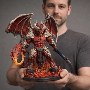 Op de afbeelding: Gedetailleerd beeldje van een rode demon met grote vleugels, hoorns en een gespierd lichaam. De demon staat op een voetstuk met vlammen, met een vurige zweep en een blauw zwaard. Het beeldje is zeer gedetailleerd.